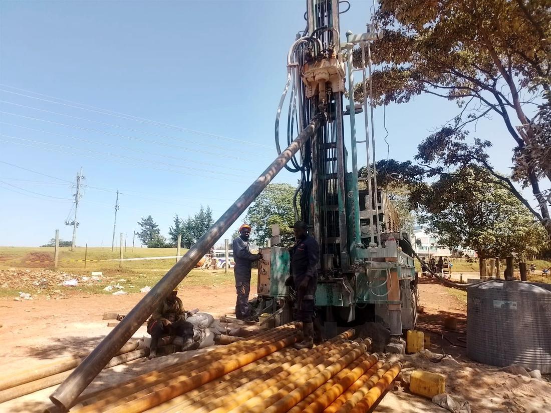 Borehole drilling rig on site with crew